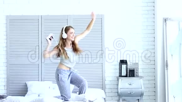 带着耳机在家听音乐的快乐年轻女子视频的预览图