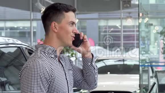 兴奋的男子微笑着拿着汽车钥匙在经销商在电话交谈视频的预览图