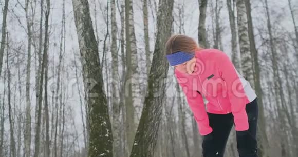一个年轻的女人在冬天的森林里晨跑累了停下来休息继续跑他恢复了体力视频的预览图