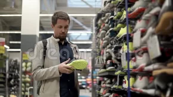 男顾客正在运动超市的货架上拿运动鞋视频的预览图