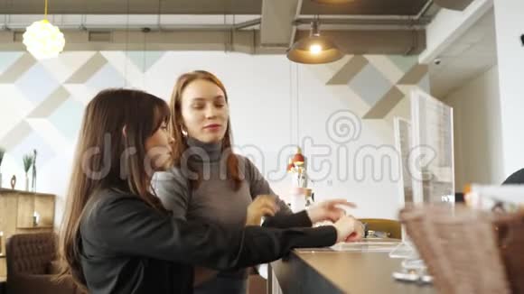 两个女人讨论菜单在酒吧柜台的咖啡馆里选择食物视频的预览图