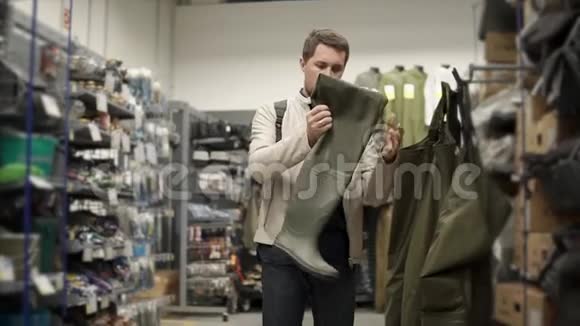 成年渔夫正在运动服装商店里挑选橡胶靴视频的预览图