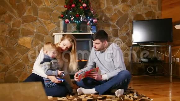 年轻幸福的家庭坐在地板上给婴儿读一本书视频的预览图