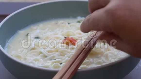 妇女用手拿筷子在碗里吃方便面它是为在饭前煮熟或泡在沸水里而设计的视频的预览图