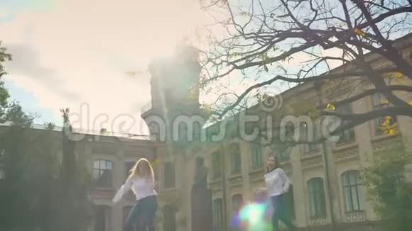 两位美丽的高加索女孩的自由舞蹈阳光明媚的日子广场上的阳光旋转的圆圈和移动的舞者视频的预览图