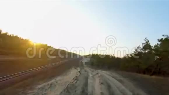 无人驾驶赛车视野日落时分飞过森林里的尘土路动态射击视频的预览图