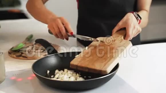 女人慢慢地把洋葱放在厨房的木砧板上视频的预览图