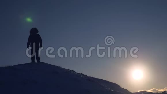 在明亮的日落下一位游客站在山上旅行时自然条件寒冷征服视频的预览图