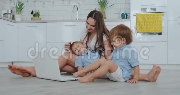 美丽的现代年轻家庭躺在家里的地板上用笔记本电脑做一些事情视频的预览图