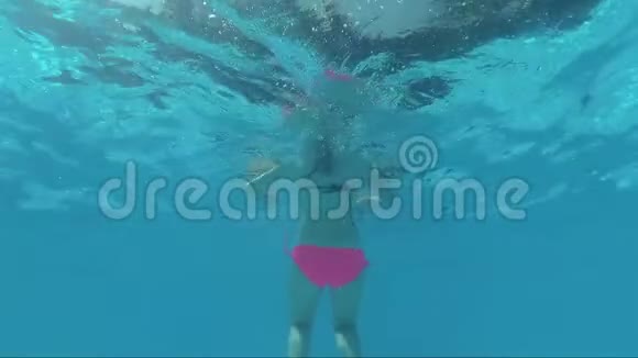 游泳池水下戴面具的快乐女孩躺在背后看着镜头视频的预览图