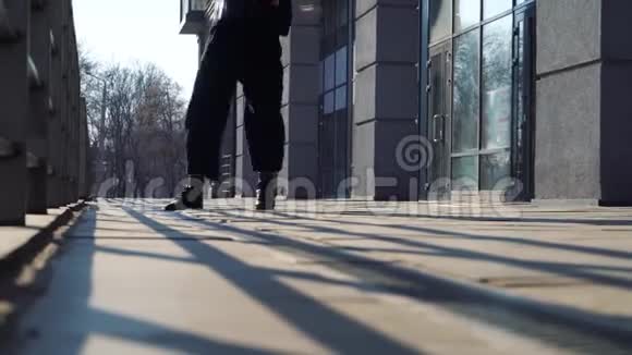 穿着黑色靴子在夕阳下的地砖上跳舞的女性腿的景色视频的预览图