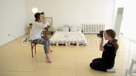 女摄影师拍摄坐在椅子上的女性模特的专业照片媒体有魅力的女摄影师视频的预览图