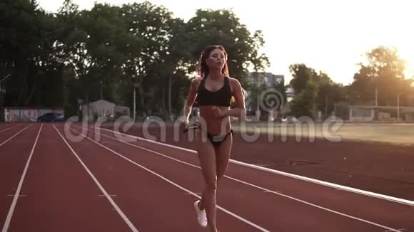 漂亮的女人完成了跑步训练站在室外体育场的跑道上休息和放松视频的预览图