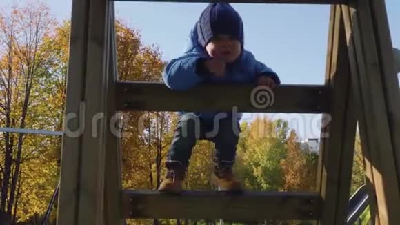 妈妈帮助幼儿在操场上爬上木梯视频的预览图