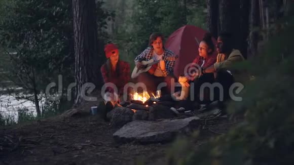 女孩和男人的朋友都在唱歌而吉他手则在森林和森林里玩乐器视频的预览图