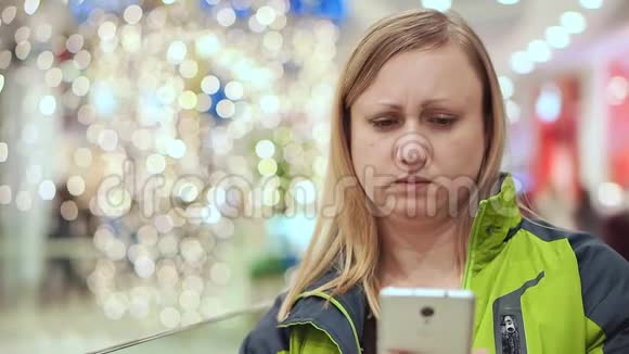 女人看了一条智能手机短信心烦意乱郁闷她站在一个商场里一个灯泡不对焦圣诞节视频的预览图