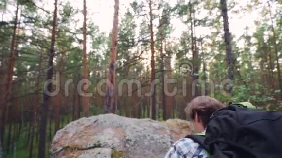 穿着旅游装备背包的帅哥正爬上岩石的顶端举起双手庆祝成功视频的预览图