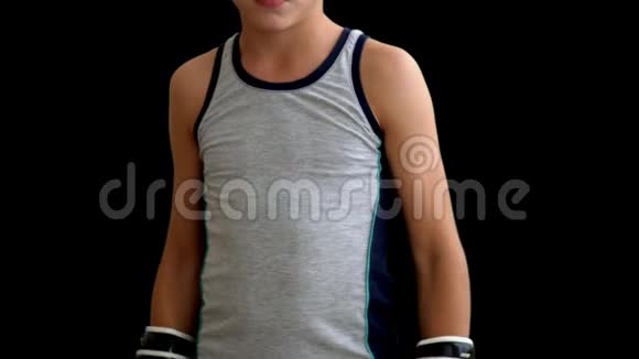 一个穿灰色运动衫的年轻拳击手站在黑暗的背景上他双手戴着手套在身体上男孩视频的预览图