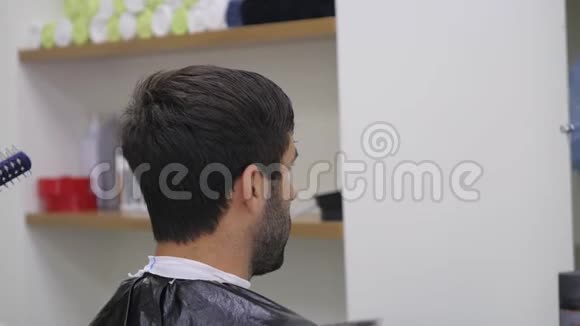 专业美发师在美容院吹风男青年顾客女理发师闭合视频的预览图