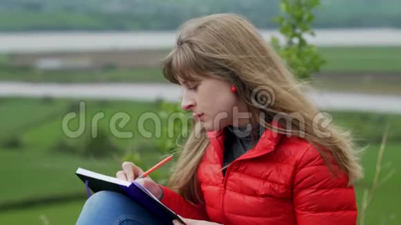 年轻女子坐在爱尔兰的绿色大自然中写笔记视频的预览图