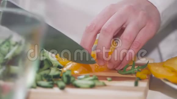 穿着白衬衫的女人在切菜板上切黄胡椒做蔬菜沙拉视频的预览图