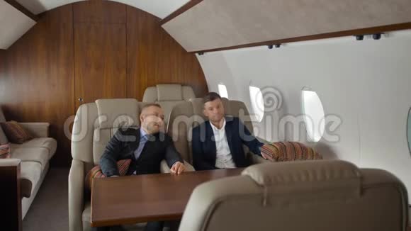 年轻的商人交谈坐在飞机内部飞行视频的预览图