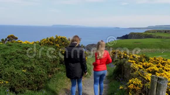 两名年轻女子沿着北爱尔兰的铜锣海岸散步视频的预览图