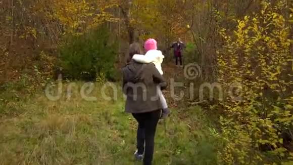 一位年轻的母亲带着她的两个孩子走过秋天的森林他们进入一片茂密而不可逾越的森林慢动作视频的预览图