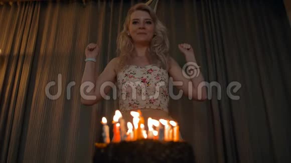 美丽的女人在节日蛋糕上吹蜡烛视频的预览图