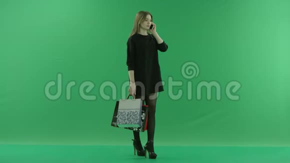 年轻迷人的女人手里拿着包在手机上说话颜色关键绿色背景视频的预览图