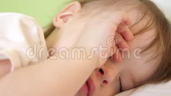 婴儿揉着眼睛想睡觉小孩子在婴儿床上睡着了视频的预览图