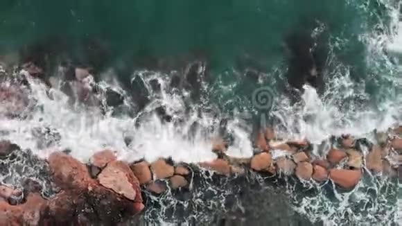 强烈海浪撞击岩石和飞溅的空中景色白色泡沫的清澈蓝色海水视频的预览图