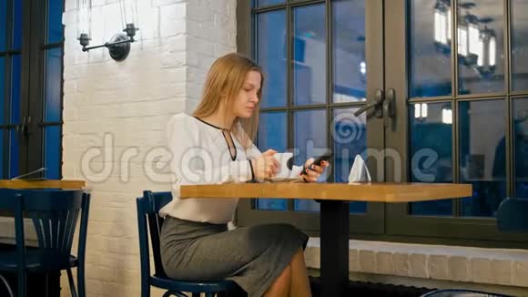 年轻商务女性在咖啡厅使用智能手机应用程序和喝咖啡视频的预览图