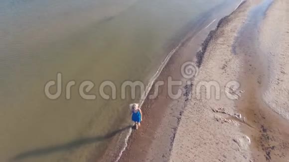清晨穿着蓝色裙子的金发碧眼在波罗的海海滩的水面上行走晴天视频的预览图