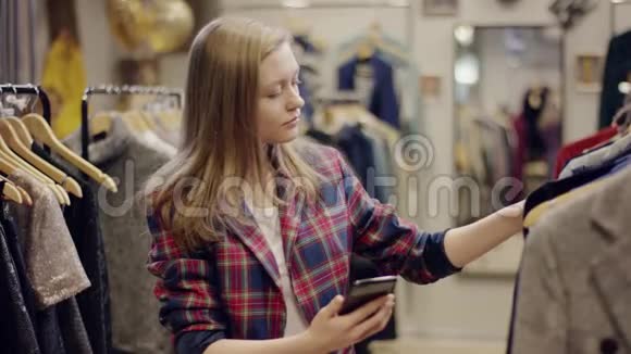 一位可爱的年轻女士在一家服装店的货架上发现一件新的漂亮衣服时她用手机视频的预览图
