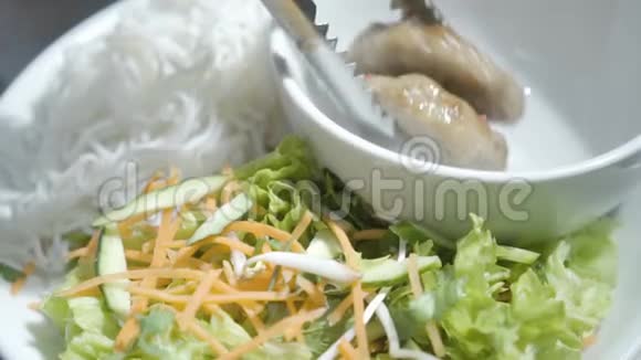 厨师手把切菜放在空碗里放在面条和胡萝卜黄瓜和维生素沙拉附近的盘子里视频的预览图