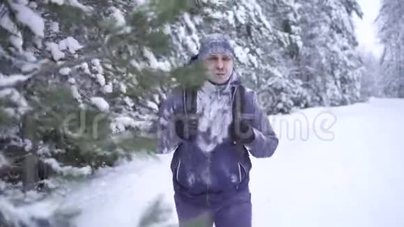 寒冷的冬天冻僵的人背着背包穿过树林视频的预览图