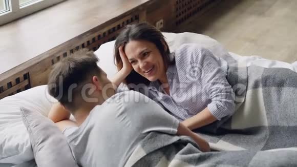 混血情侣躺在床上聊天漂亮的亚洲女人在和丈夫说话笑着视频的预览图