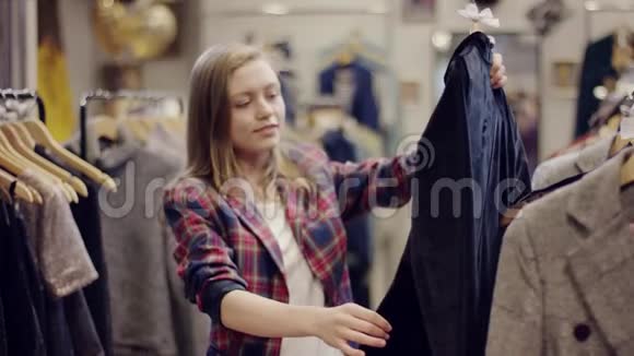 迷人的年轻女子在服装店检查黑白相间的衣服视频的预览图