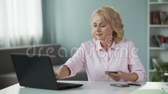 50岁以上的妇女输入自己的信用卡数据在网上支付公用事业服务费用视频的预览图