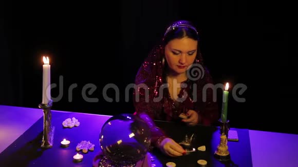 在神奇的沙龙里吉普赛人点燃黑桌上的蜡烛视频的预览图