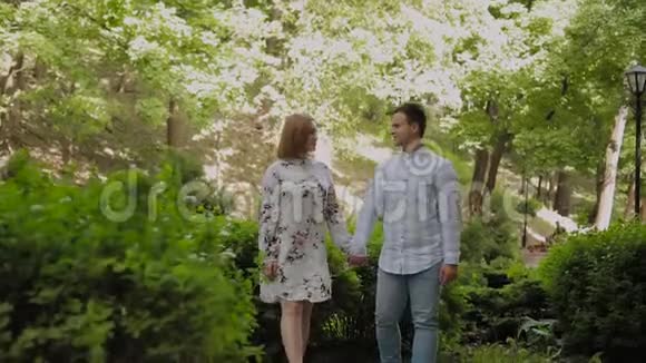 美丽幸福的年轻夫妇在阳光明媚的天气里穿过公园视频的预览图