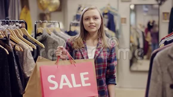 年轻快乐的女顾客手里拿着印有销售字样的购物袋正站在镜头前视频的预览图