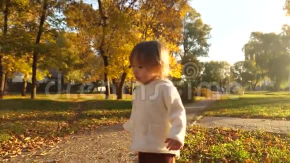 小孩子在秋天的公园里草坪和干草上跑步快乐的小宝宝晚上在街上散步视频的预览图