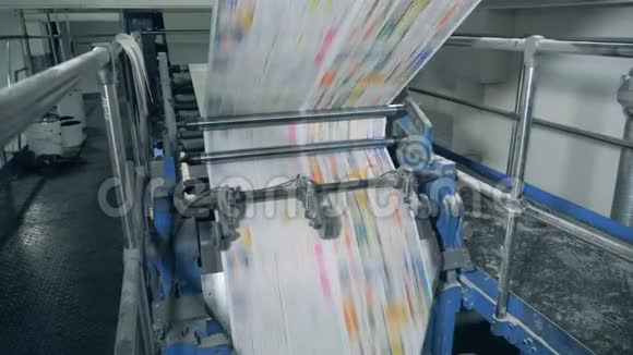 报纸页在印刷办公室的机械传送带上滚动视频的预览图