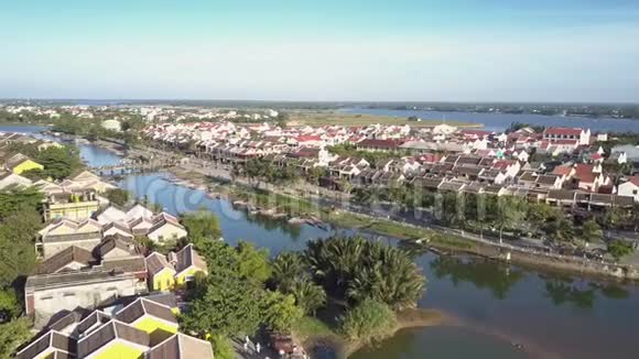在平静的蓝色河流和绿色河岸附近的鸟瞰房屋视频的预览图