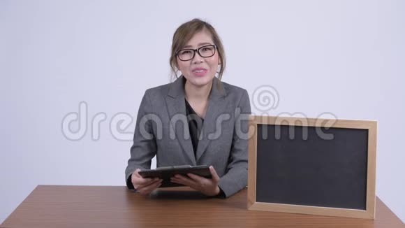 年轻快乐的亚洲女商人在桌上展示黑板视频的预览图