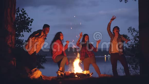 周末在森林里欢乐的朋友多民族的人围着火堆跳舞青年视频的预览图