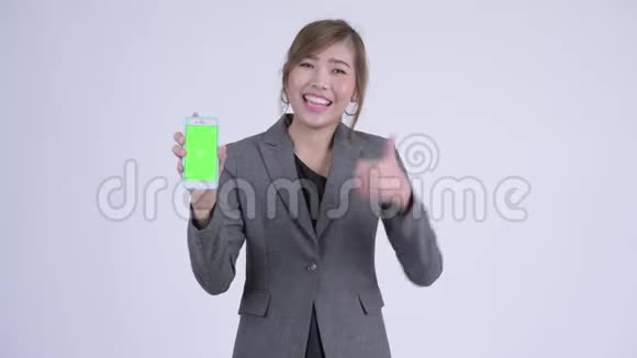 年轻快乐的亚洲女商人带着电话竖起大拇指视频的预览图