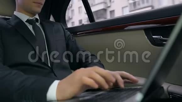 自信的商人坐在汽车后座上使用笔记本电脑工作项目视频的预览图